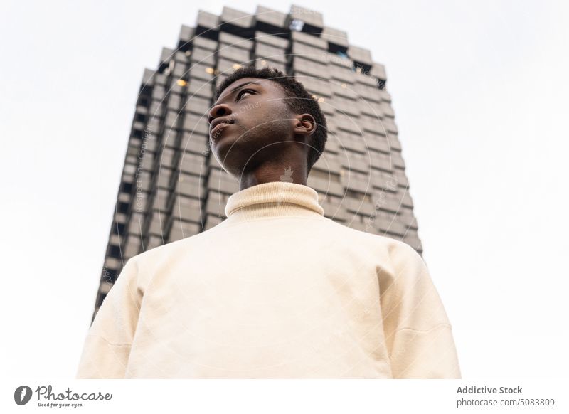 Ernster schwarzer Mann in der Nähe eines modernen Gebäudes ernst Straße urban Individualität nachdenklich nachdenken selbstbewusst männlich stehen Stoff