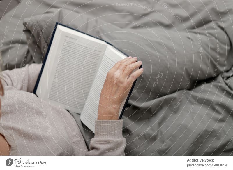 Anonyme ältere Frau, die auf dem Bett ein Buch liest Rentnerin lesen Literatur Kopfkissen Schlafzimmer Hobby Etage ruhen sich[Akk] entspannen heimwärts Komfort