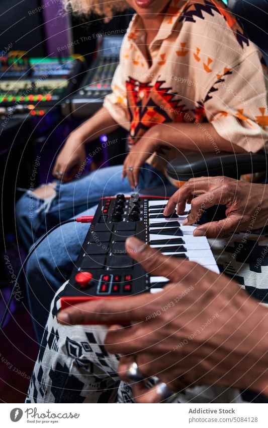 Anonymer schwarzer Mann spielt Synthesizer, während eine Frau im Aufnahmestudio zusieht spielen Musik Hobby genießen Aufzeichnen Atelier Probe Mixer Gesang