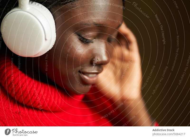 Lächelnder afroamerikanischer Teenager mit Kopfhörern Frau Model benutzend zuhören Musik Gesang Glück Spaß haben Studioaufnahme Individualität Apparatur