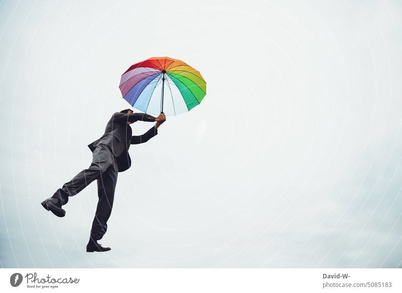 Mann fliegt mit einem Schirm durch die Luft Regenschirm fliegen träumen Traum Kreativität Wolken Himmel Freiheit Schwerelosigkeit frei bunt Schweben Glück