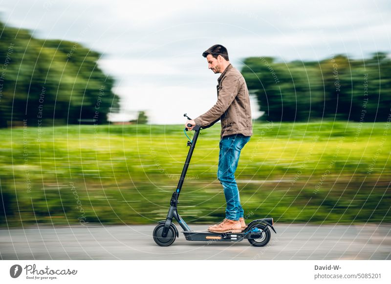 Mann fährt mit dem E-Scooter E-Roller fahren schnell Geschwindigkeit Spaß nachhaltig umweltfreundlich innovativ Natur draußen Straße Mobilität