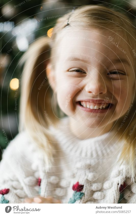 Kleines Mädchen mit Zöpfen lächelnd vor einem Weihnachtsbaum Weihnachtsmann Hintergrund blond hell Feier Kind Kindheit Weihnachten niedlich Dezember