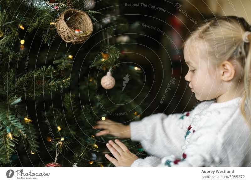 Kleinkind Mädchen mit Zöpfen setzen Ornamente auf einem Weihnachtsbaum Weihnachtsmann Hintergrund blond hell Feier Kind Kindheit Weihnachten niedlich Dezember