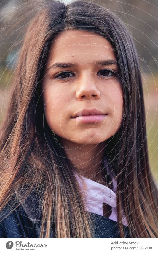 Stilvolles Teenager-Mädchen mit langen Haaren im Park stehend Metall Konstruktion Herbst Natur Zeitvertreib Laubwerk Windstille Kälte allein Inhalt ethnisch
