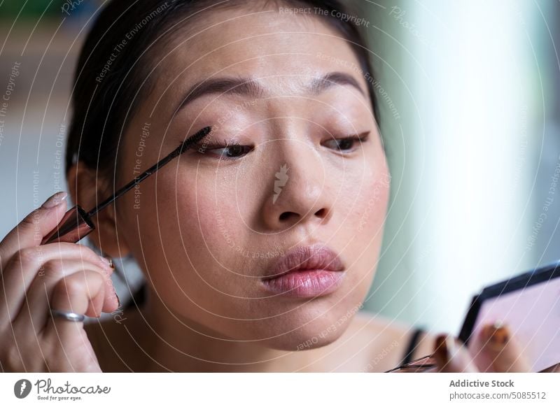 Professionelle asiatische Visagistin trägt Mascara auf die Wimpern auf visagiste professionell Wimperntusche Frau bewerben Bürste Palette Spiegel Kosmetik