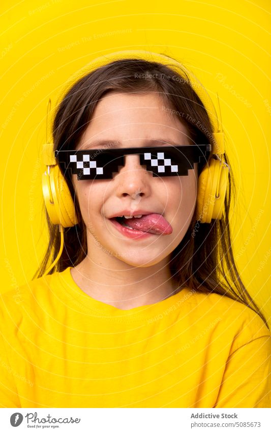 Mädchen mit Kopfhörern und Pixelbrille Kind zuhören Musik Bildpunkt Brille Studioaufnahme ausspannen Gerät Lächeln genießen positiv heiter Schulmädchen