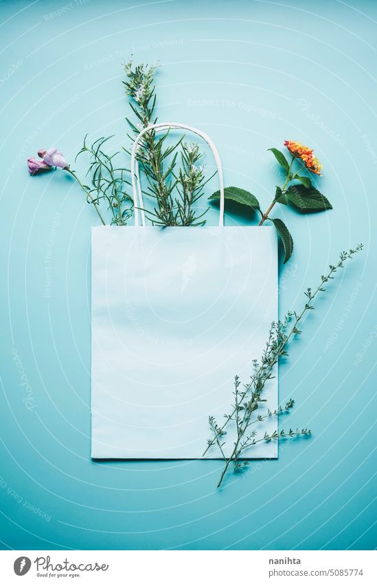 Saisonale Mockup eines blauen Papier-Geschenk-Tasche von Blumen in Flat-Lay-Format umgeben Attrappe flache Verlegung Hintergrund Frühling Natur natürlich