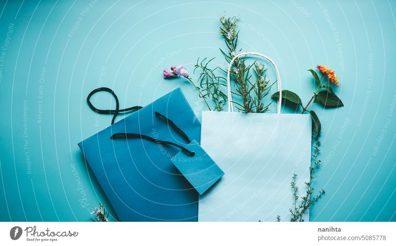 Saisonale Mockup eines blauen Papier-Geschenk-Tasche von Blumen in Flat-Lay-Format umgeben Attrappe flache Verlegung Hintergrund Frühling Natur natürlich