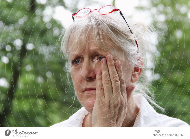 Zahnschmerzen - Porträt einer Seniorin mit grauem Haar, die eine Hand an ihre schmerzende Wange hält Mensch Frau Blick Gesicht Haare grauhaarig Brille draußen
