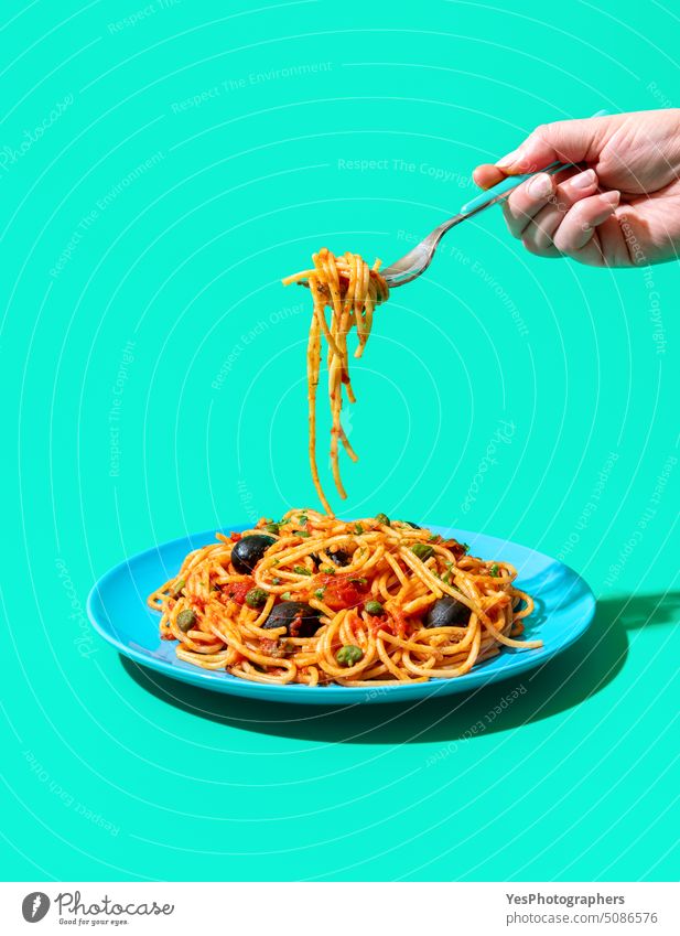 Pasta puttanesca Teller minimalistisch auf einem grünen Hintergrund. Essen vegane Pasta. blau hell Kapriolen Kohlenhydrate Farbe gekocht Textfreiraum kreativ
