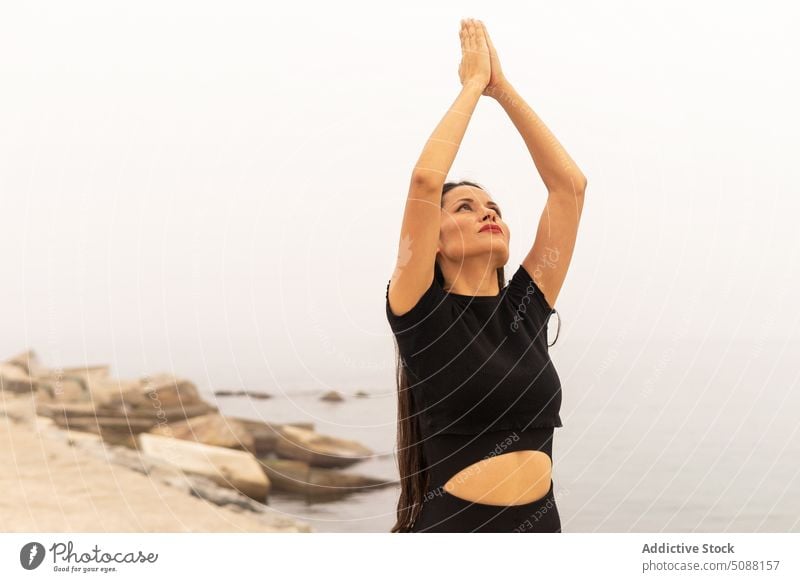 Schlanke Frau beim Yoga, die ihre Hände zur Namaste-Geste erhebt üben Asana halbmondförmiger Ausfallschritt ashta chandrasana MEER Nebel Harmonie Windstille