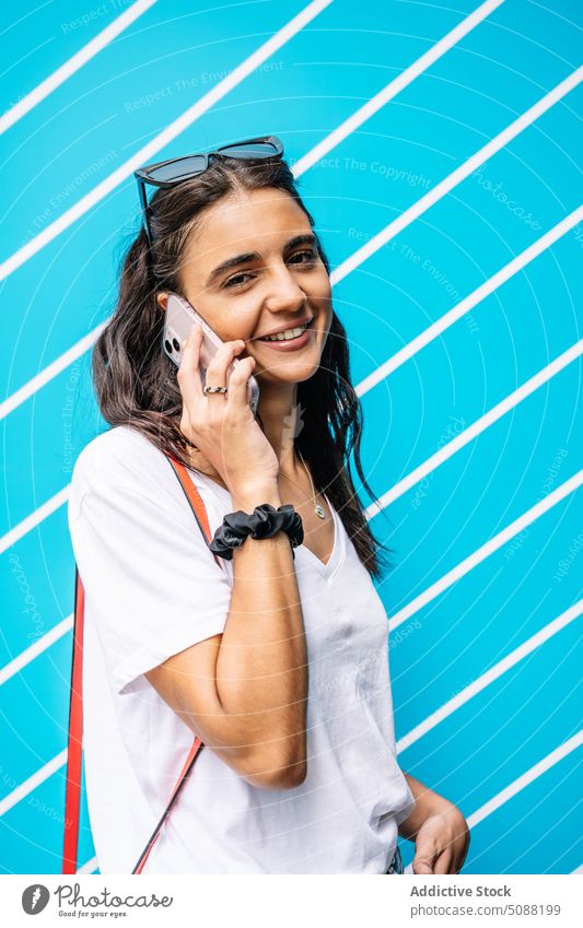 Glückliche Frau spricht mit Smartphone in der Nähe der Wand mit Linien reden heiter Gespräch Mobile Telefon Lächeln jung sprechen Apparatur Kommunizieren froh