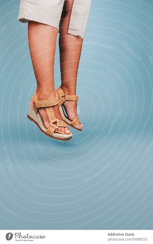 Crop Frau springt gegen blauen Hintergrund springen Sandale Kleid Energie Sommer Stil in der Luft Model Aktivität Schuhe Accessoire Paar dynamisch
