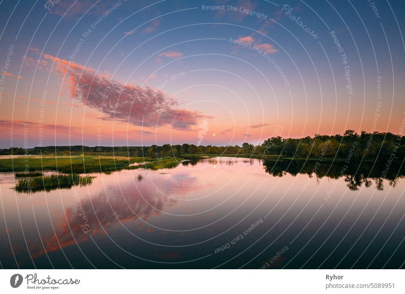 Flusslandschaft in Weißrussland oder europäischen Teil von Russland in Sonnenuntergang Zeit der Sommerabend. Moon Rising über Wasser See oder Fluss. Natur am sonnigen Abend.