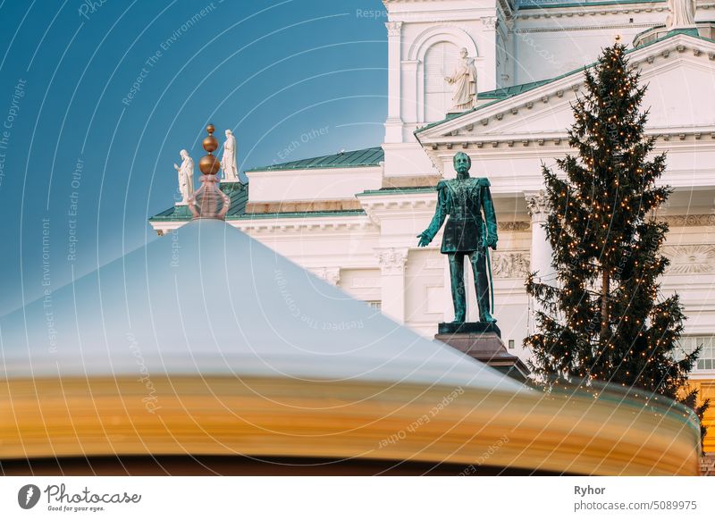 Helsinki, Finnland. Weihnachten Xmas Holiday Karussell auf dem Senatsplatz in der Nähe von berühmten Wahrzeichen. Lutherische Kathedrale und Denkmal für den russischen Zaren Alexander II.