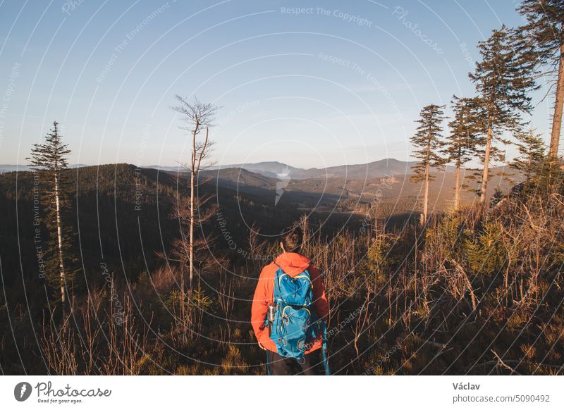 Ein aktiver Wanderer genießt das Gefühl, bei Sonnenaufgang den Gipfel des Berges zu erreichen. Ein Wanderer wird von der Morgensonne erleuchtet und genießt den Blick auf das Tal. Beskiden, Tschechische Republik