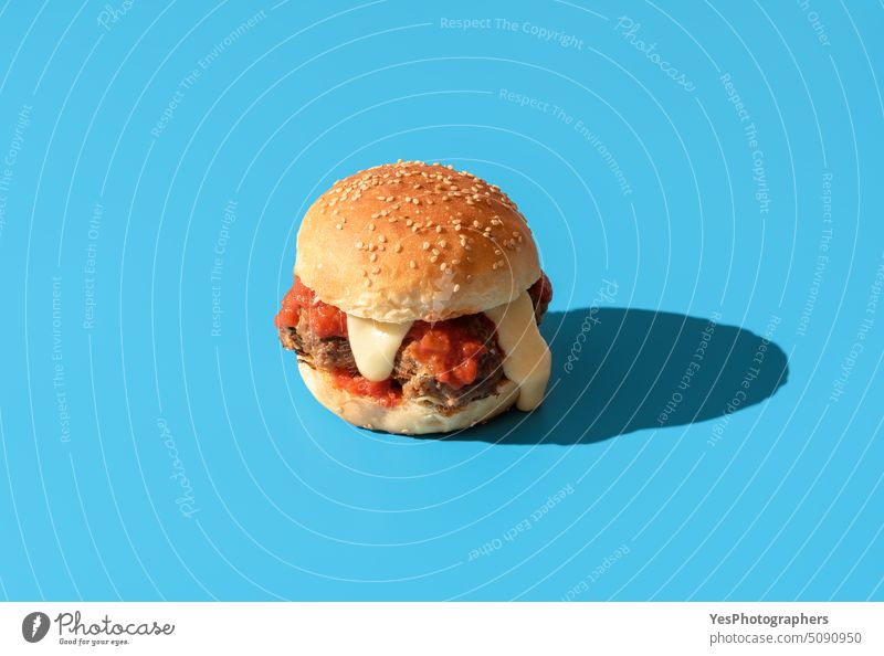 Burger mit Fleischbällchen isoliert auf blauem Hintergrund oben Rindfleisch Brot hell Brötchen Kalorien Cheddar Käse Cheeseburger Farbe Textfreiraum Küche