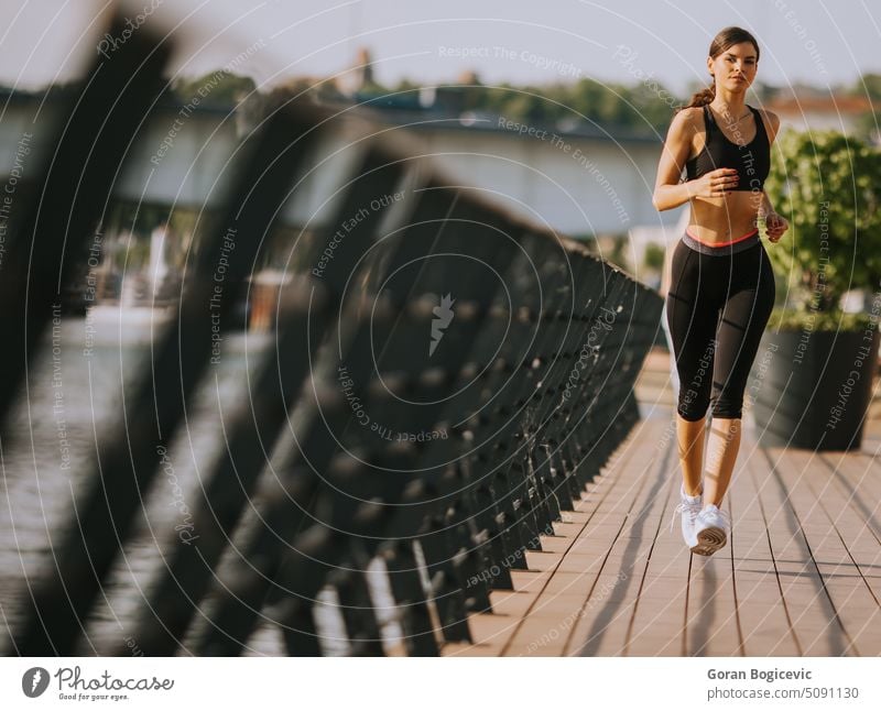 Aktive junge schöne Frau läuft auf der Promenade am Flussufer entlang aktiv Aktivität Athlet sportlich Großstadt Ausdauer Übung Fitness Gesundheit in Jogger