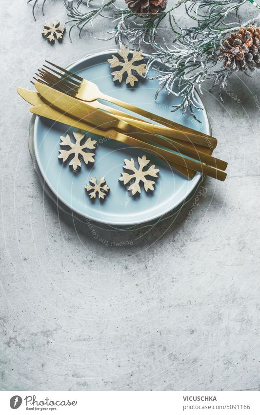 Weihnachtlich gedeckter Tisch mit goldenem Besteck, blauem Teller und Schneeflocken Dekoration, Ansicht von oben Weihnachten Tabelleneinstellung blaues Schild