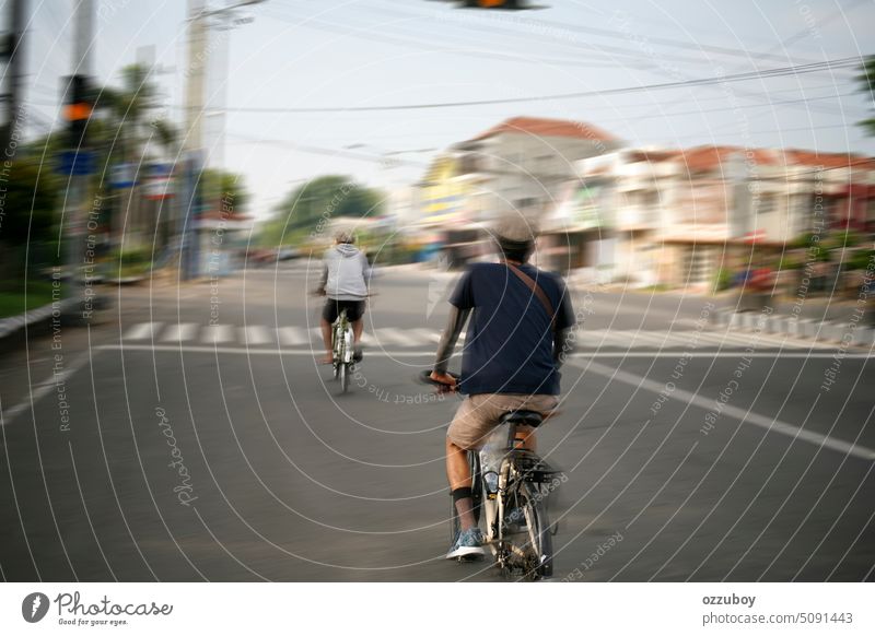 Bewegungsunschärfe von zwei Personen beim Fahrradfahren in einer asiatischen Straße. Rückansicht. Mann im Freien Mitfahrgelegenheit männlich Sport Großstadt
