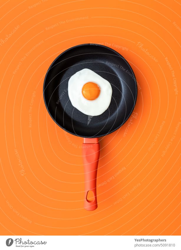Spiegelei in einer Kochpfanne, Draufsicht auf orangefarbenem Hintergrund oben Frühstück hell Farbe Konzept Essen zubereiten Textfreiraum kreativ Küche