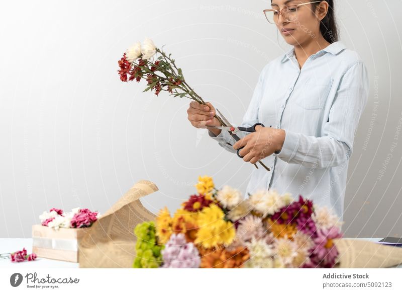 Positiv gestimmte Blumenhändlerin, die einen Blumenstrauß arrangiert Frau geschnitten Vorbau einrichten Handwerk Papier festlich präsentieren kreativ geblümt