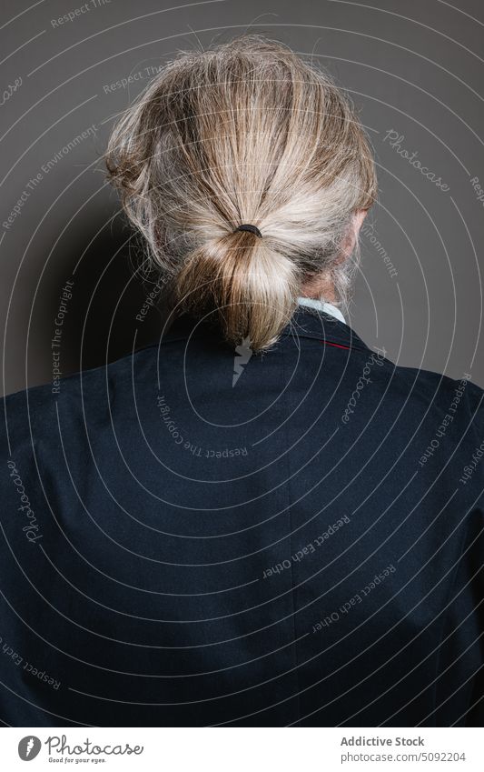 Älterer grauhaariger Mann steht mit dem Rücken zugewandt Studioaufnahme Kavalier Pferdeschwanz graues Haar Anzug Jacke intelligent Frisur Senior älter gealtert