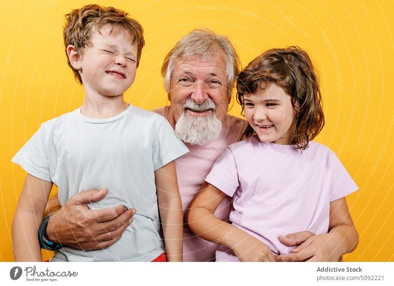 Glücklicher Großvater mit Enkelkindern auf gelbem Hintergrund Mann Umarmen Umarmung Lachen Liebe schließen Bonden Partnerschaft genießen Lächeln heiter positiv