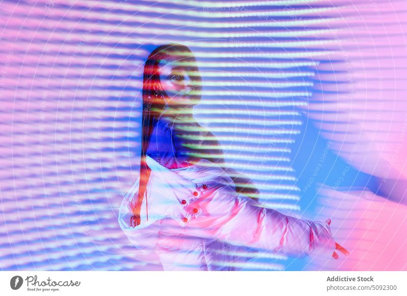 Stilvolle ethnische weibliche Jugendliche stehen in Neon Studio Frau selbstbewusst cool selbstsicher ernst sich[Akk] bewegen neonfarbig Model glühen