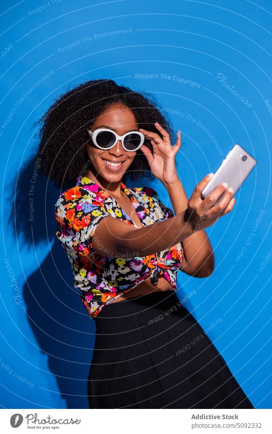 Stilvolle afroamerikanische Frau nimmt Selfie Lächeln Smartphone ausrichten Sonnenbrille Glück farbenfroh hell jung schwarz Afroamerikaner ethnisch modern