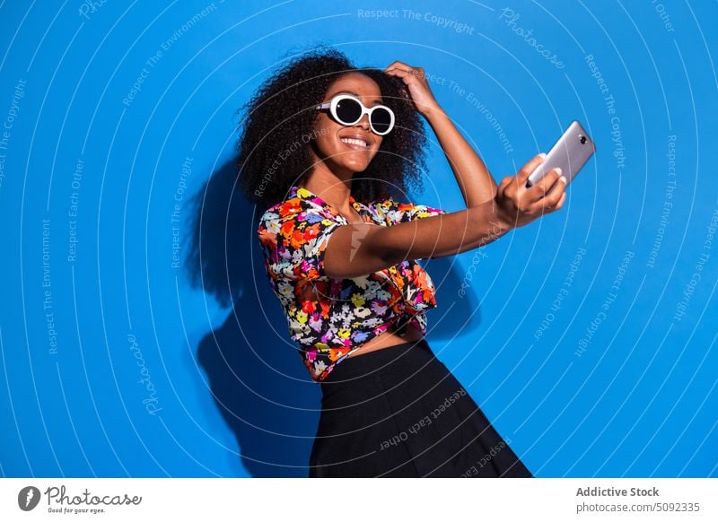 Stilvolle afroamerikanische Frau nimmt Selfie Lächeln Smartphone ausrichten Sonnenbrille Glück farbenfroh hell jung schwarz Afroamerikaner ethnisch modern
