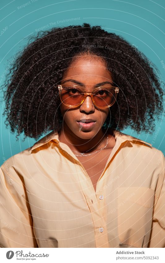 Stylisches schwarzes Modell in Hemd und Sonnenbrille Frau Stil Vorschein krause Haare ernst Porträt farbenfroh hell Afroamerikaner ethnisch jung Individualität