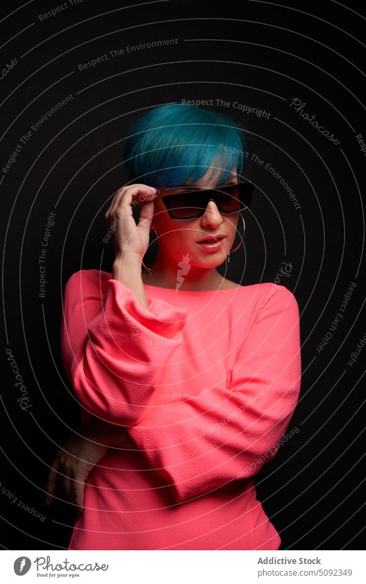 Moderne Frau beim Einstellen der Sonnenbrille im Studio Stil trendy Model cool selbstbewusst Individualität modern Hipster Glanzlicht blaue Haare Kurze Haare