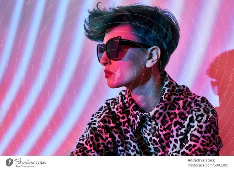 Stilvolle Frau mit Sonnenbrille und Neonröhren trendy Hipster Licht Mode neonfarbig Outfit Instrument Melodie purpur Frisur Brille modern rosa Hobby Talent