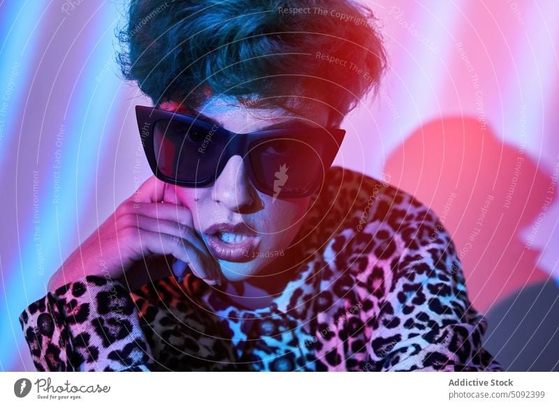 Stilvolle Frau mit Sonnenbrille und Neonröhren Porträt trendy neonfarbig Licht Model selbstbewusst Einstellung farbenfroh Outfit Wand Vorschein modern