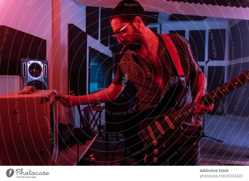 Mann, der einen Verstärker benutzt und E-Gitarre spielt elektrisch ausrichten Musik Atelier Gitarrenspieler Musiker leuchten männlich modern Klang Hobby