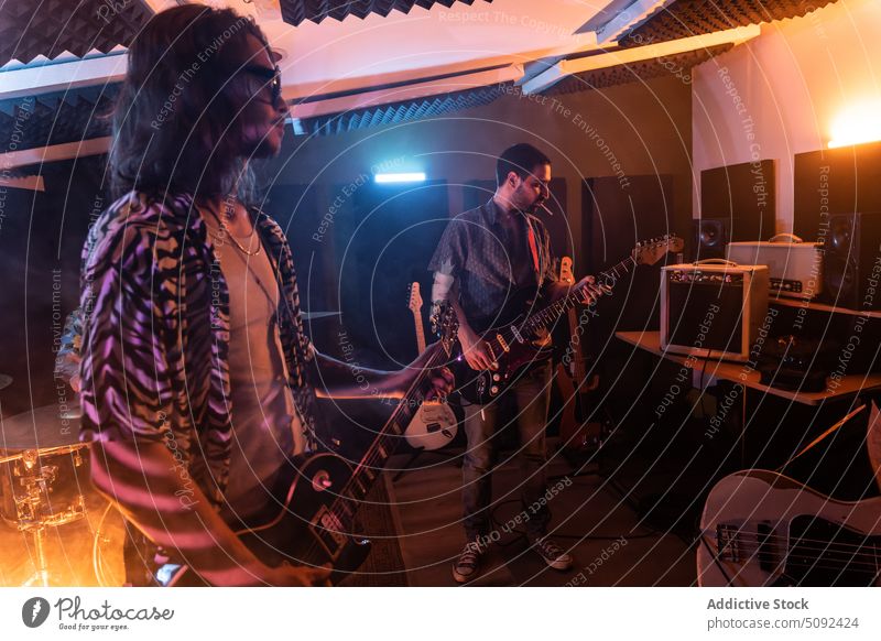Männliche Freunde spielen E-Gitarren im Studio Männer elektrisch Musik Musiker Atelier Fähigkeit Probe Band modern ausführen leuchten Instrument männlich Klang