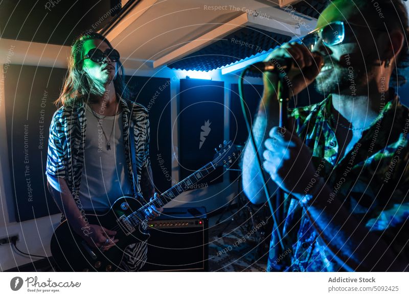 Stylische Rockband bei einem nächtlichen Auftritt in einem Club Männer Sänger Gitarrenspieler spielen Band Musik Probe Musiker ausführen singen elektrisch Stil