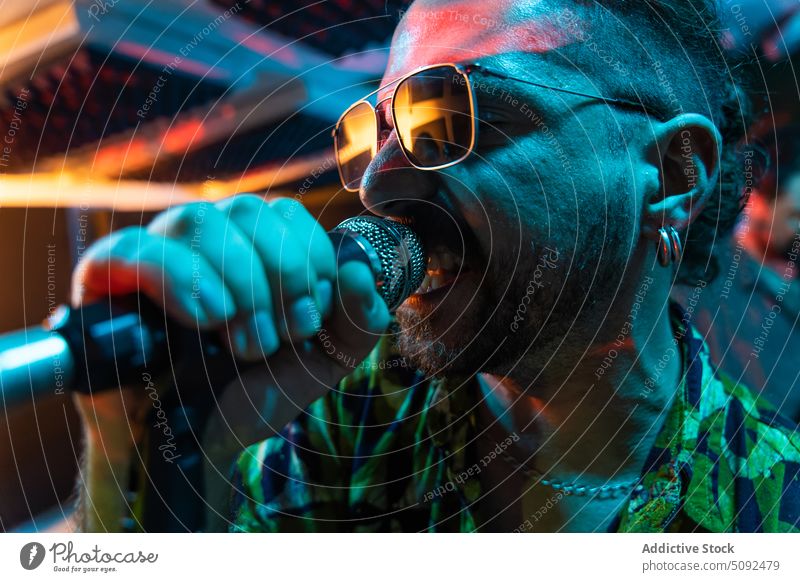 Mann mit Sonnenbrille singt im Studio ins Mikrofon Sängerin singen Gesang Stimme ausführen Probe Talent Atelier Musik Energie modern Musiker Aufzeichnen üben