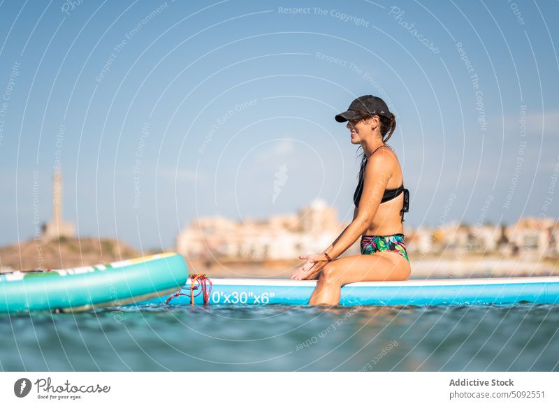 Fit Frau sitzt auf Paddleboard Paddelbrett Dehnung Lächeln Zusatzplatine MEER passen froh Sport Gesundheit Aktivität Sommer Erholung Unschärfe Wasser Glück