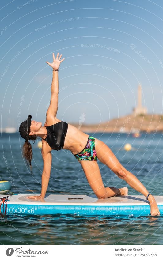 Fit Frau macht Yoga auf Paddleboard Gleichgewicht Zusatzplatine Paddelbrett MEER Wasser Gesundheit Übung Aktivität üben Seitliche Planke auf dem Knie