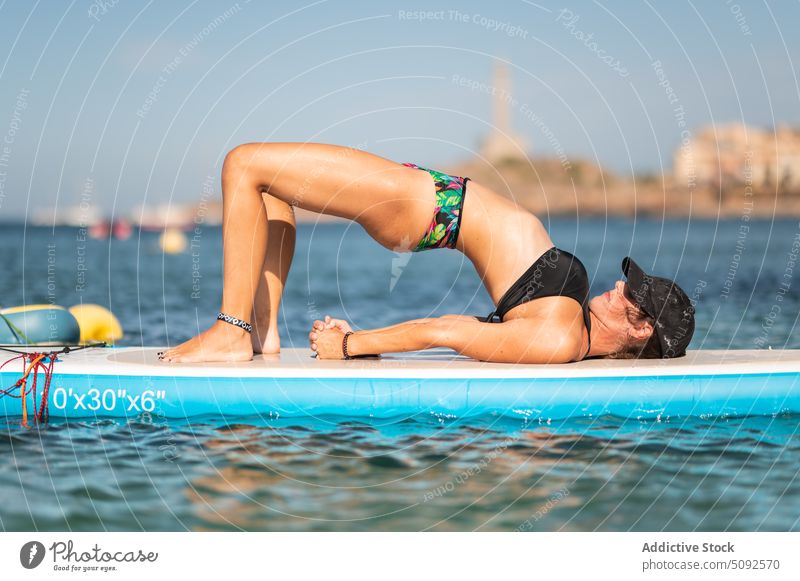 Fit Frau macht Yoga Asana auf Paddleboard im Meer üben Gleichgewicht Zusatzplatine Paddelbrett MEER Badebekleidung Gesundheit Sommer Aktivität Wellness passen