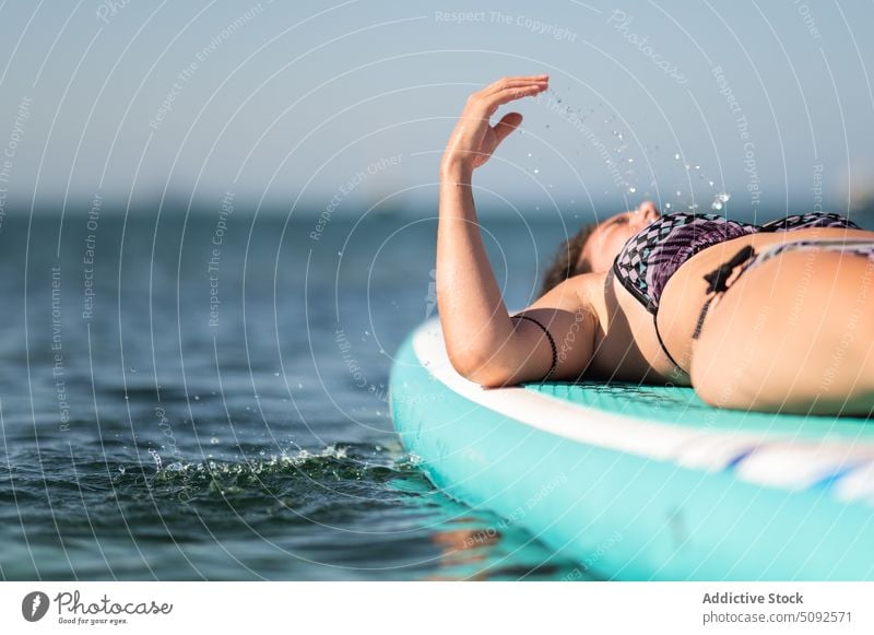 Frau entspannt sich auf Paddleboard im Meerwasser Paddelbrett Bräune Zusatzplatine Kälte ruhen Schwimmer MEER Wasser Windstille Lügen Urlaub Sommer Sonnenbad