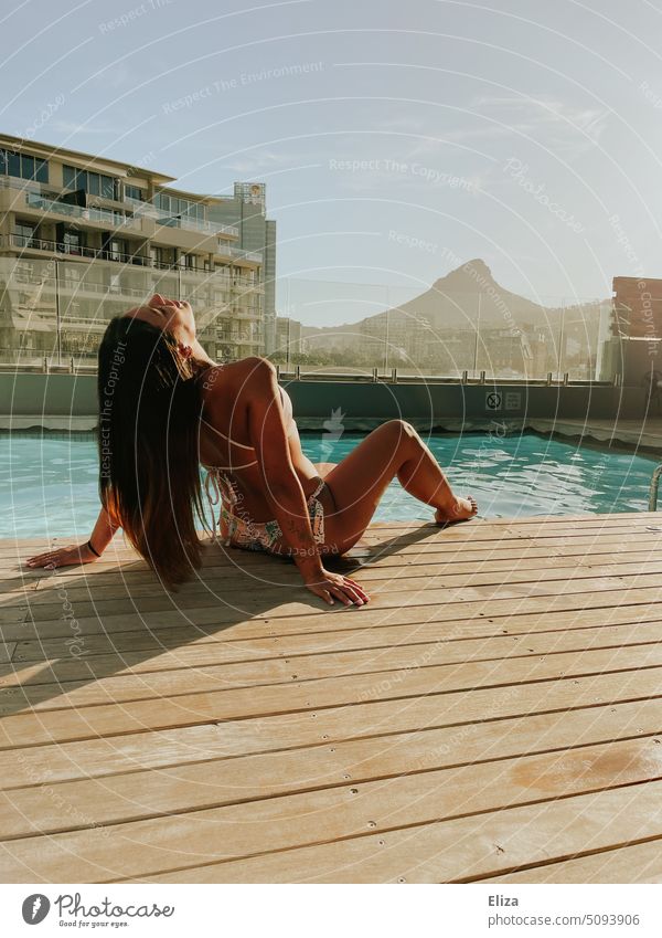 Frau räkelt sich im Bikini am Pool mit Blick auf den Lions Rock in Kapstadt Hotel Urlaub Sommer Erholung Lifestyle schön jung räkeln gebräunt Sonnenlicht