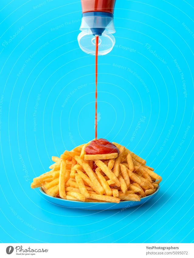 Ketchup-Sauce über Pommes frites gießen, isoliert auf blauem Hintergrund Überfluss hell Kalorien Farbe Konzept Textfreiraum Knusprig Küche ausschneiden