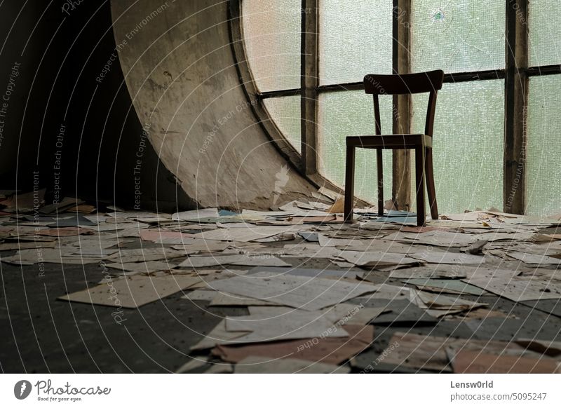 Stuhl vor einem runden Fenster in einer verlassenen Kirche mit Papieren und Buchseiten, die auf dem Boden liegen Verlassen verlassene Kirche verlassenes Haus