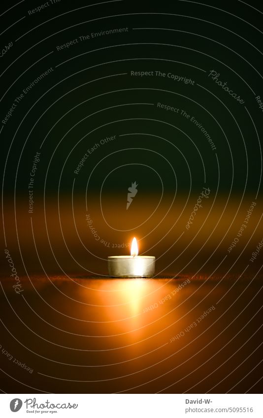 ein brennendes Teelicht in der Dunkelheit Kerze Weihnachten & Advent Kerzenschein Licht Erinnerung Gedenken Glaube besinnlich Hoffnung Kerzenflamme Platzhalter