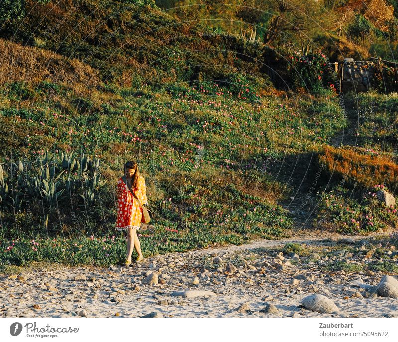 Frau im orangefarbenen Kleid spaziert auf einem kleinen Pfad zum Strand Sonne Weg Gedanken sonnig Urlaub reisen Sommer Erholung Landschaft entspannt schön Sand