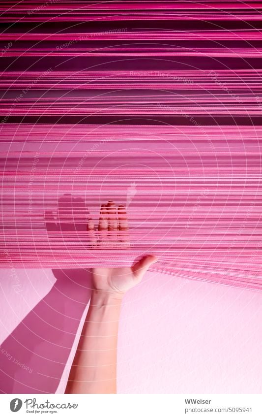 Eine weibliche Hand hebt energisch einen Vorhang aus rosa und pinkfarbenen Strippen an Geste Zeichen Frau Power Emanzipation stark frei halten heben befreien